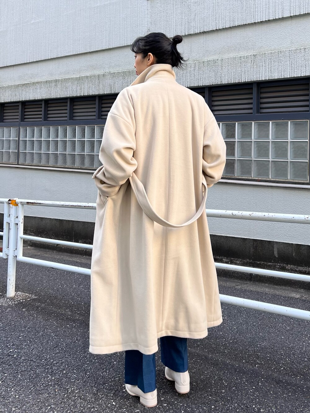 ベージュ系のステンカラーコート、ホワイト系のベスト、ホワイト系のニット/セーターを着用したレディースの秋コーディネートの3枚目の写真