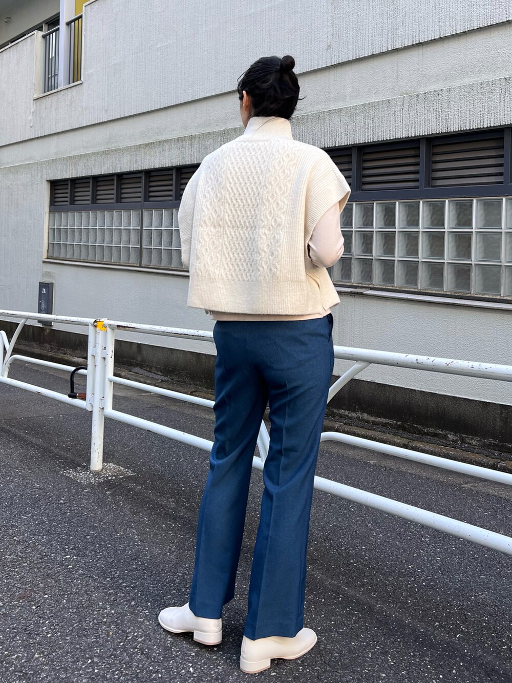 ベージュ系のステンカラーコート、ホワイト系のベスト、ホワイト系のニット/セーターを着用したレディースの秋コーディネートの5枚目の写真