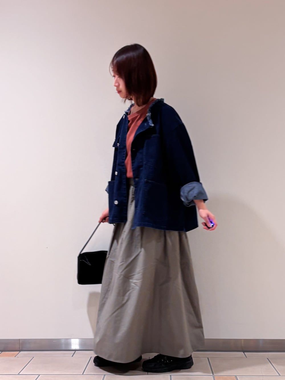 ブルー系のデニムジャケット、レッド系のTシャツ/カットソー、グリーン系のスカートを着用したレディースの秋コーディネートの3枚目の写真