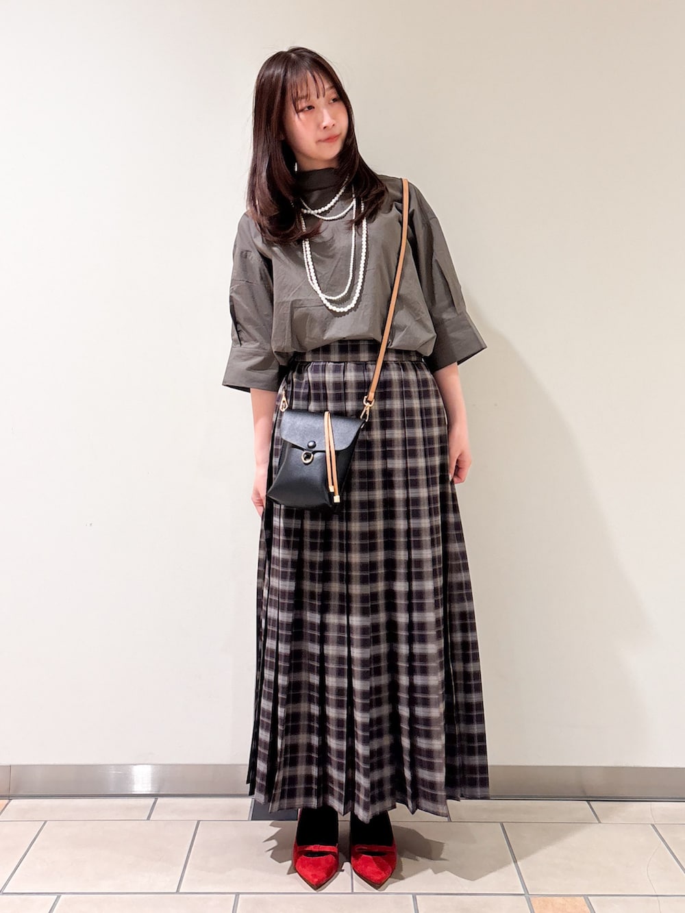 レッド系のパンプス、ブラック系のショルダーバッグ、グレー系のシャツ/ブラウスを着用したレディースの春コーディネートの2枚目の写真