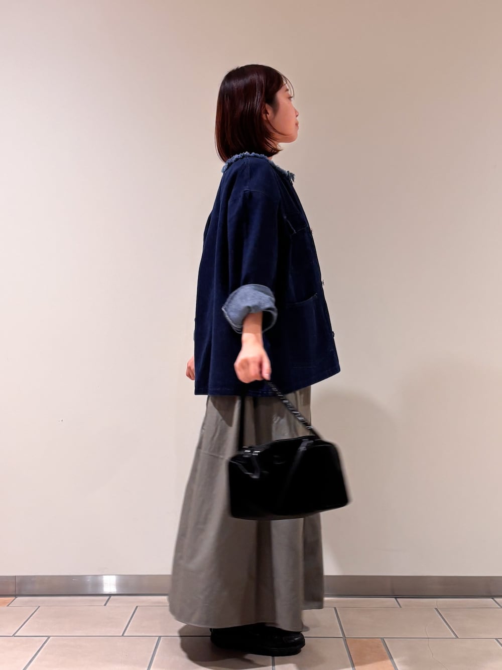 ブルー系のデニムジャケット、レッド系のTシャツ/カットソー、グリーン系のスカートを着用したレディースの秋コーディネートの2枚目の写真
