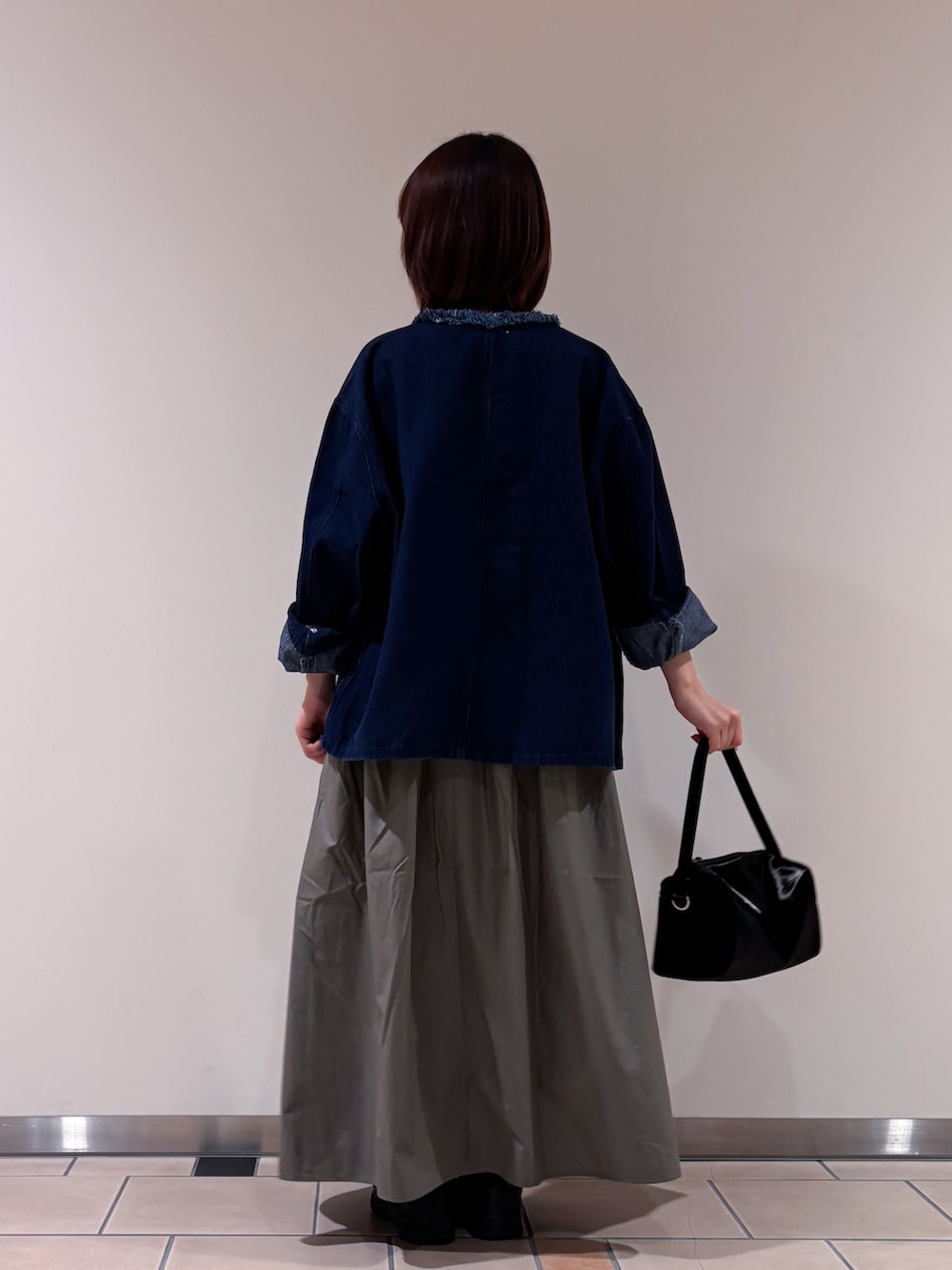 ブルー系のデニムジャケット、レッド系のTシャツ/カットソー、グリーン系のスカートを着用したレディースの秋コーディネートの4枚目の写真