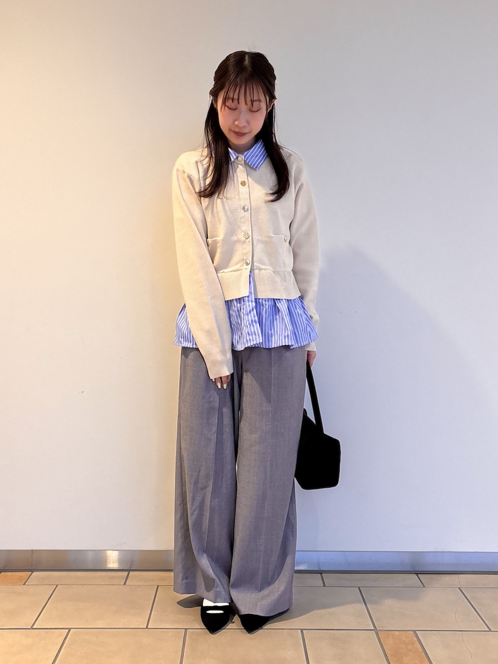 ホワイト系のニット/セーター、グレー系のその他パンツ、ブラック系のトートバッグを着用したレディースの春コーディネートの2枚目の写真