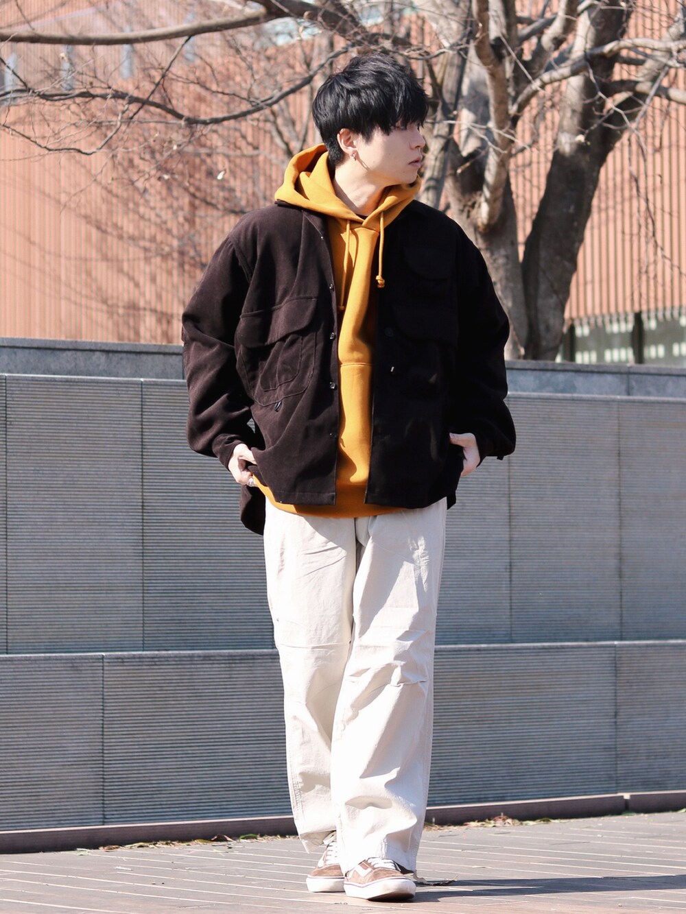 ブラウン系のスニーカー、ブラウン系のミリタリージャケット、オレンジ系のパーカーを着用したメンズの冬コーディネートの2枚目の写真