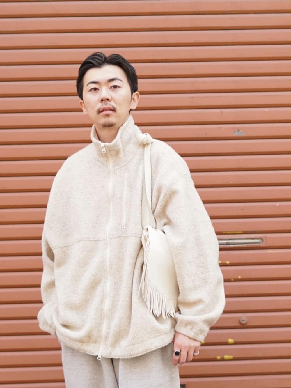 ホワイト系のブルゾン、グレー系のスウェットパンツ、ブラック系のブーツを着用したメンズの冬コーディネートの2枚目の写真