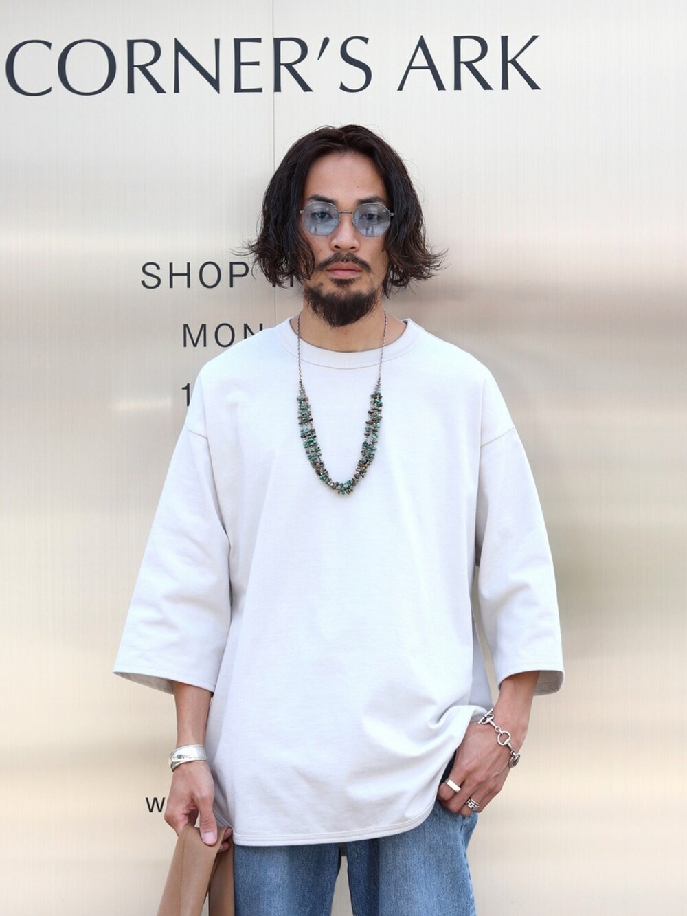 ホワイト系のTシャツ/カットソー、ブルー系のデニムパンツ、ブラウン系のトートバッグを着用したメンズの夏コーディネートの2枚目の写真