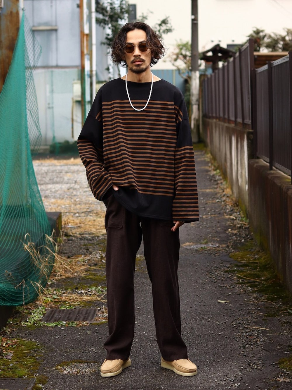 ブラック系のTシャツ/カットソー、オレンジ系のカーディガン/ボレロ、ブラウン系のチノパンツを着用したメンズの冬コーディネートの2枚目の写真