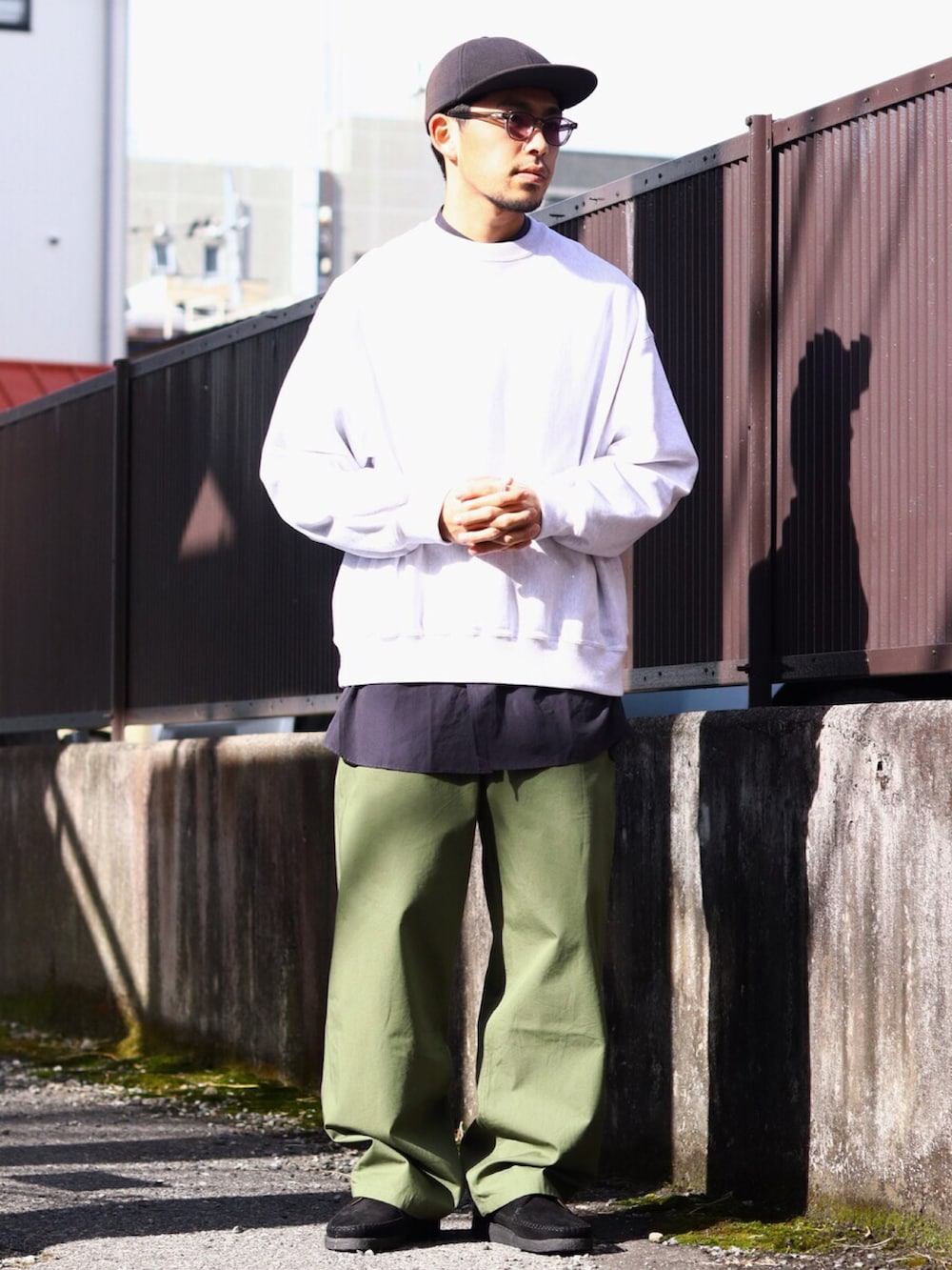 ベージュ系のノーカラーコート、グリーン系のカーゴパンツを着用したメンズの冬コーディネートの2枚目の写真