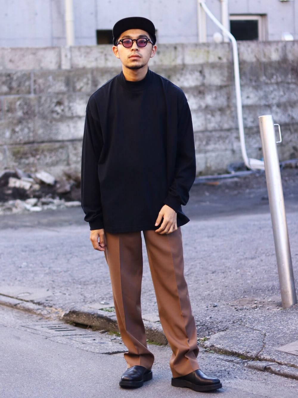 ブラウン系のテーラードジャケット、ブラック系のニット/セーター、ブラウン系のスラックスを着用したメンズの冬コーディネートの2枚目の写真