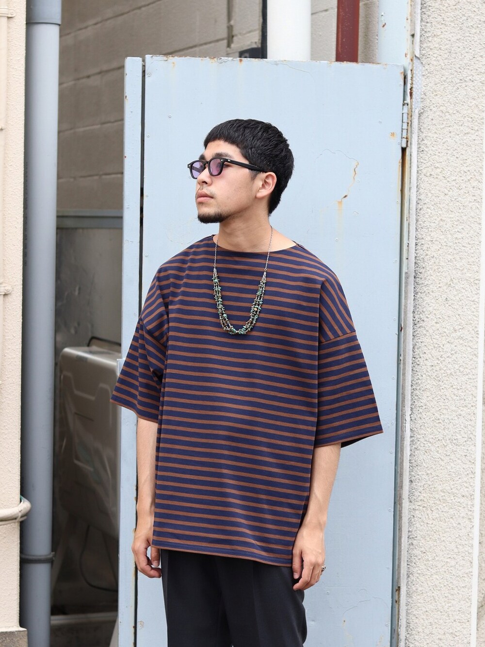 ブルー系のTシャツ/カットソー、グレー系のスラックスを着用したメンズの夏コーディネートの2枚目の写真