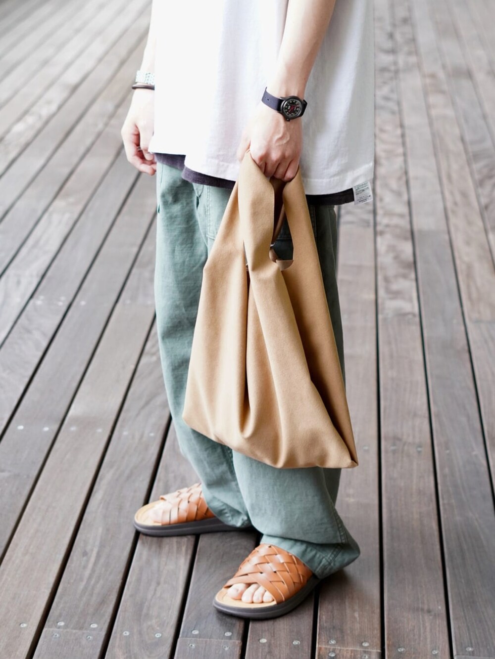 ホワイト系のTシャツ/カットソー、ブラウン系のトートバッグ、グリーン系のその他パンツを着用したメンズの春コーディネートの2枚目の写真