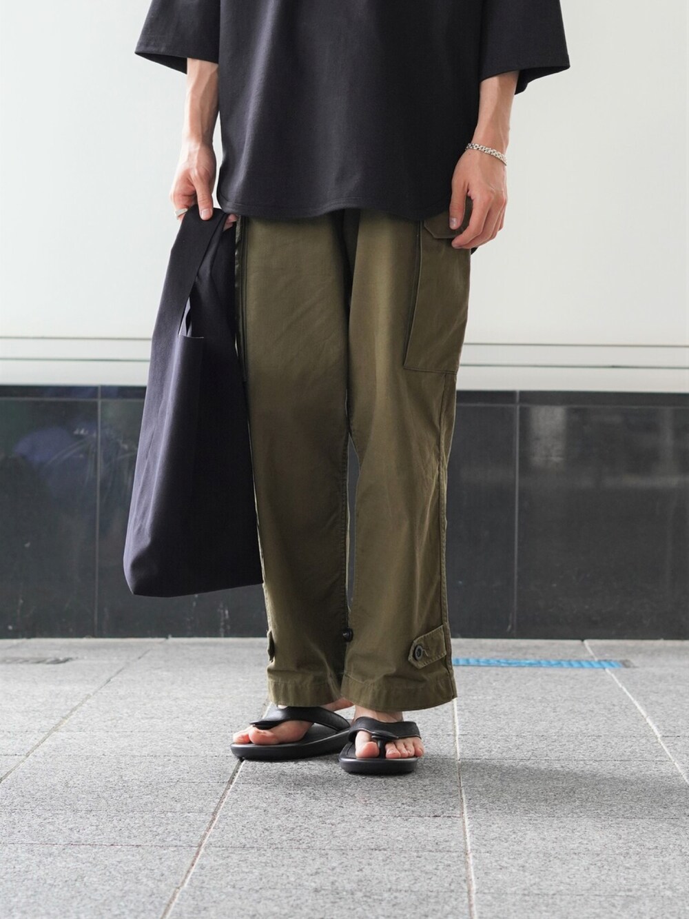 ブラック系のTシャツ/カットソー、グリーン系のカーゴパンツ、ブラック系のトートバッグを着用したメンズの夏コーディネートの4枚目の写真
