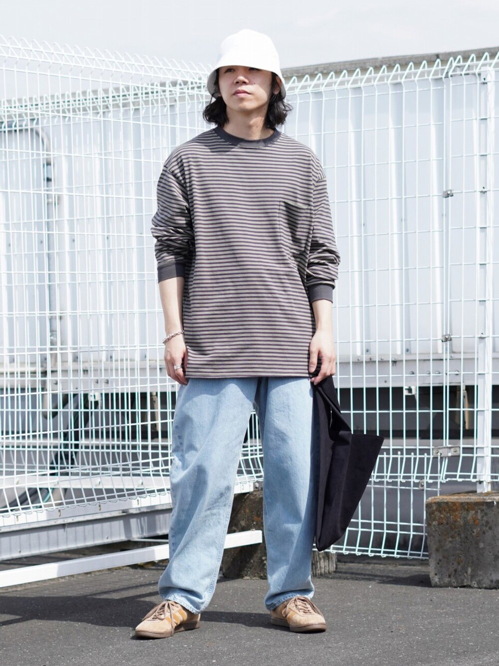 グレー系のTシャツ/カットソー、ホワイト系のデニムパンツ、ブラック系のトートバッグを着用したメンズの春コーディネートの2枚目の写真