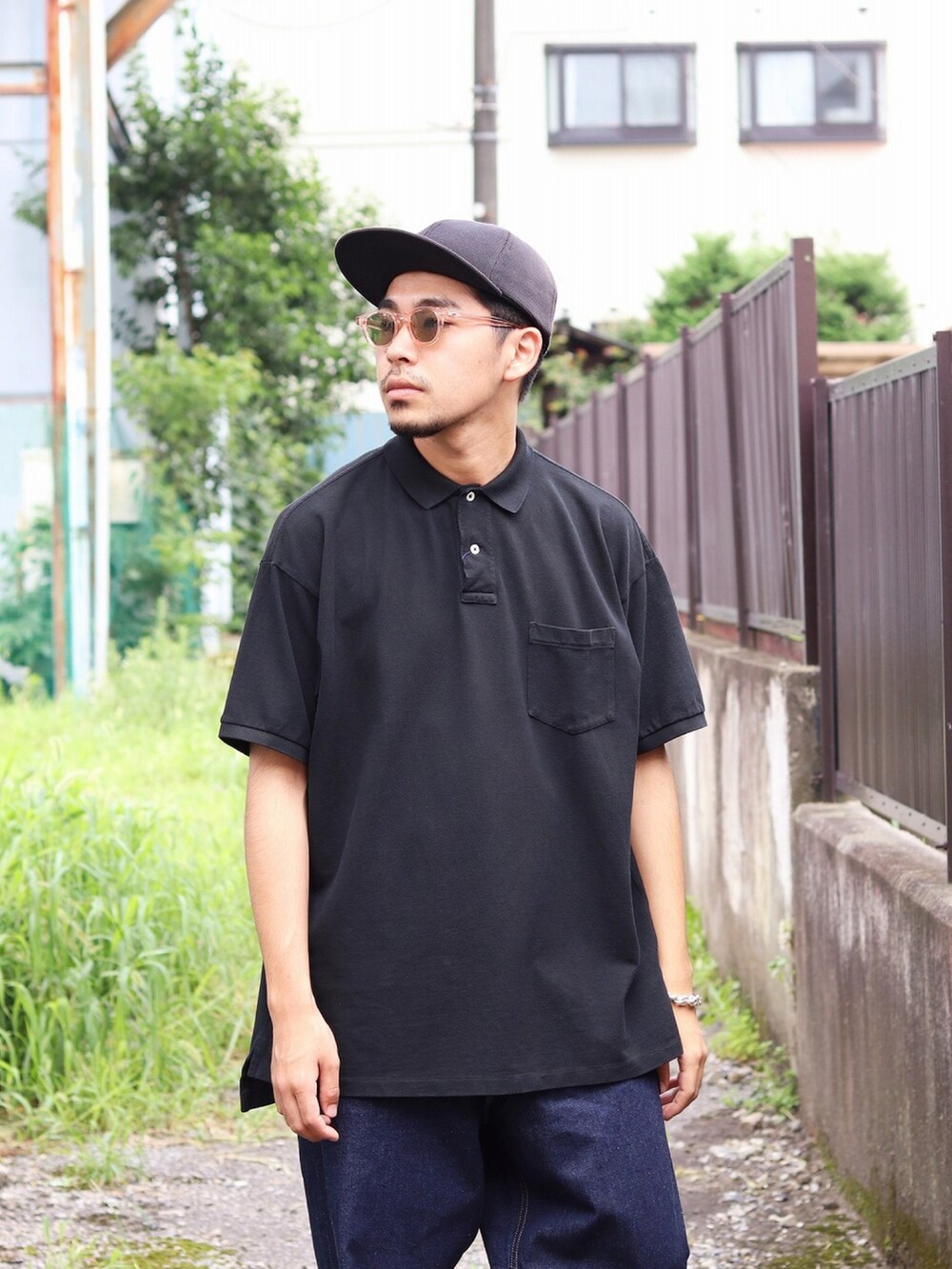 ブラック系のポロシャツ、ブルー系のデニムパンツを着用したメンズの夏コーディネートの2枚目の写真