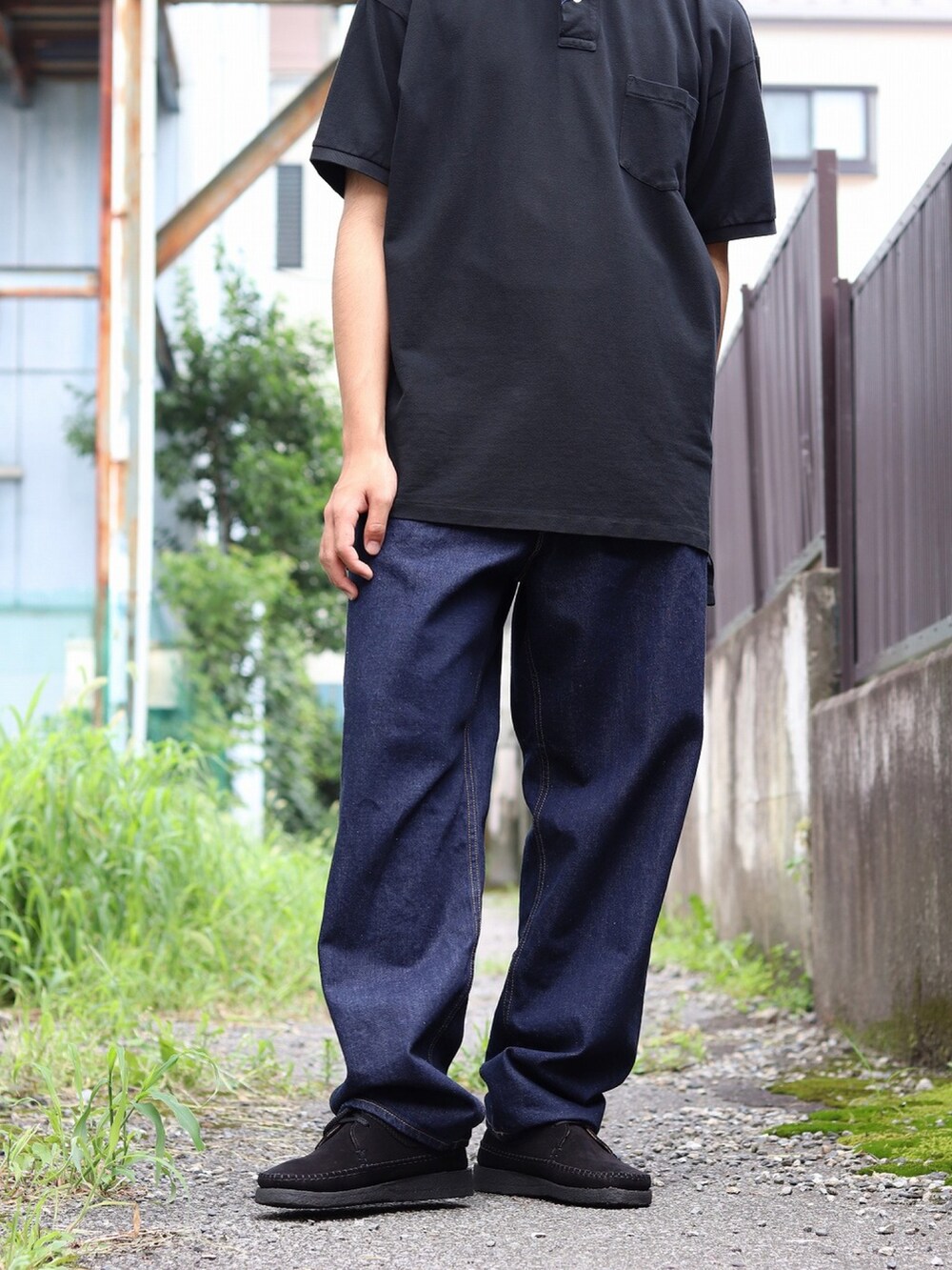 ブラック系のポロシャツ、ブルー系のデニムパンツを着用したメンズの夏コーディネートの3枚目の写真