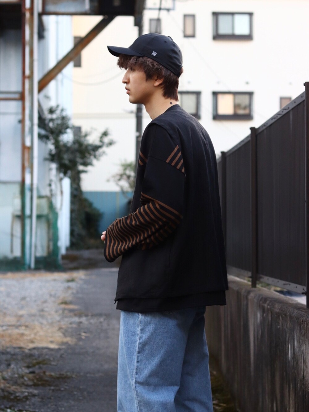 ブラック系のTシャツ/カットソー、ブラック系のベスト、ブルー系のデニムパンツを着用したメンズの冬コーディネートの2枚目の写真