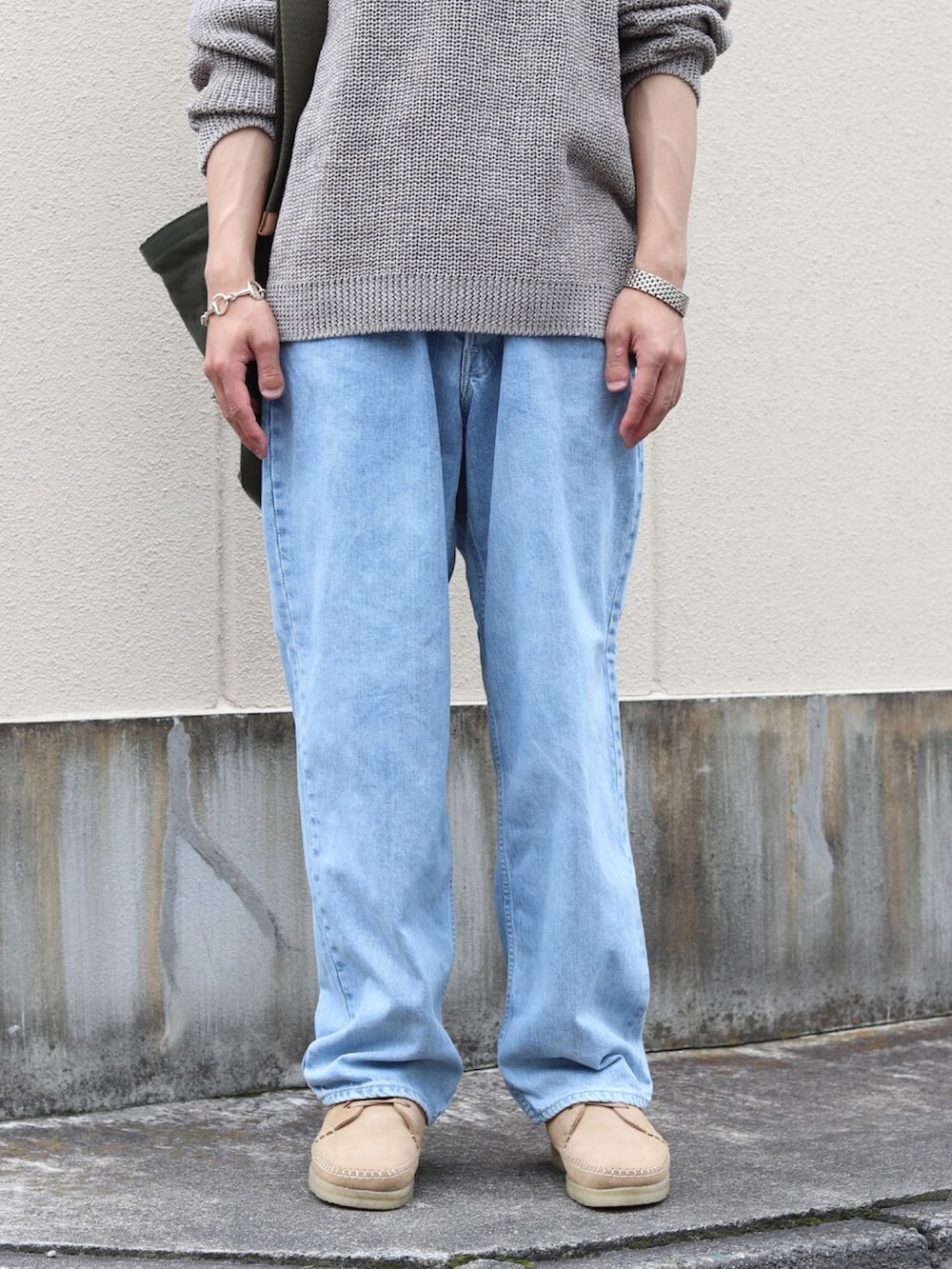 グレー系のニット/セーター、ブルー系のデニムパンツ、グリーン系のショルダーバッグを着用したメンズの夏コーディネートの3枚目の写真