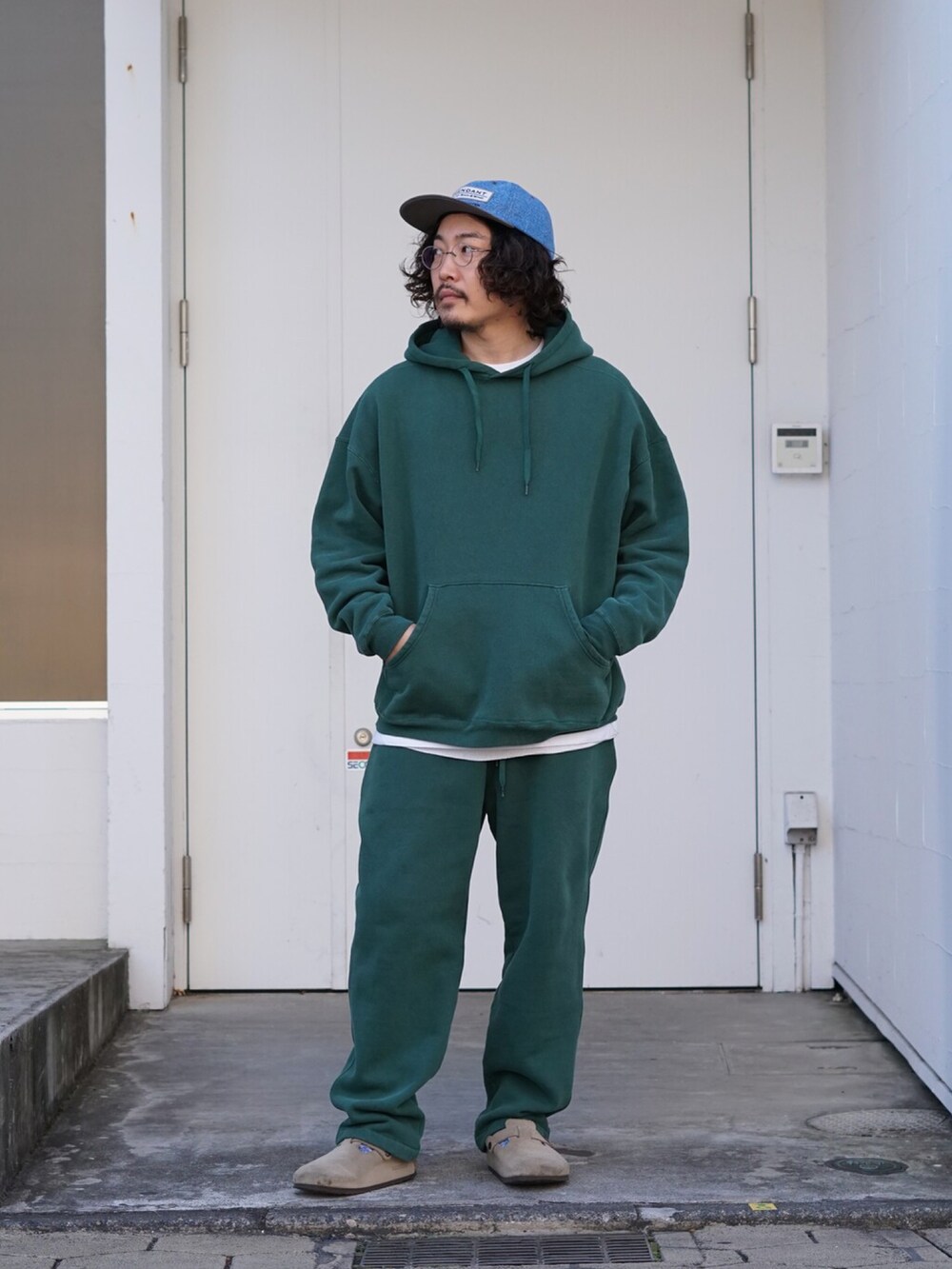 グリーン系のパーカー、グリーン系のスウェットパンツ、ベージュ系のサンダルを着用したメンズの秋コーディネートの2枚目の写真