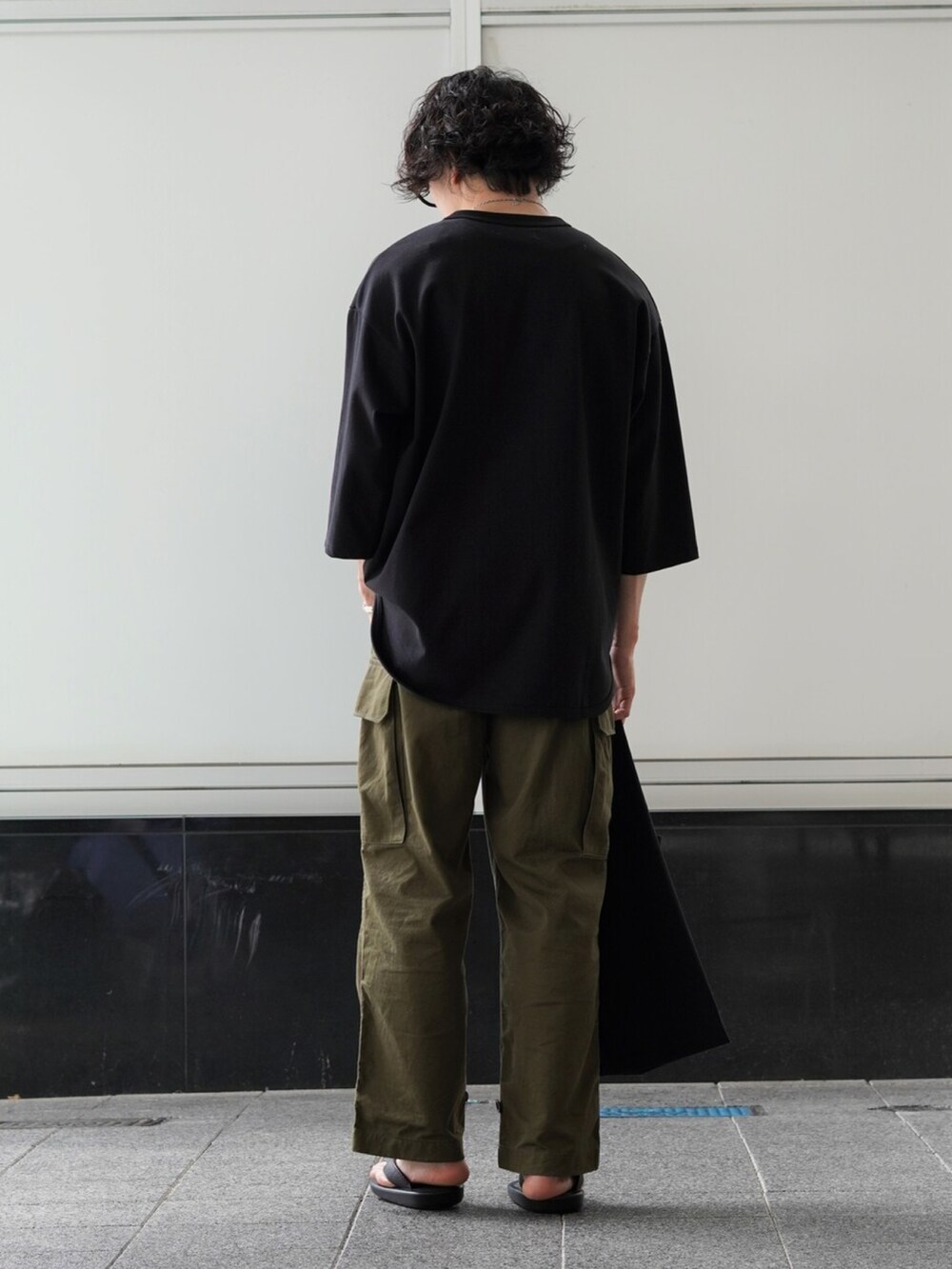 ブラック系のTシャツ/カットソー、グリーン系のカーゴパンツ、ブラック系のトートバッグを着用したメンズの夏コーディネートの3枚目の写真