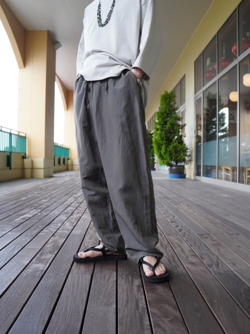 ホワイト系のTシャツ/カットソー、グレー系のスラックス、ブラック系のトートバッグを着用したメンズの夏コーディネートの3枚目の写真