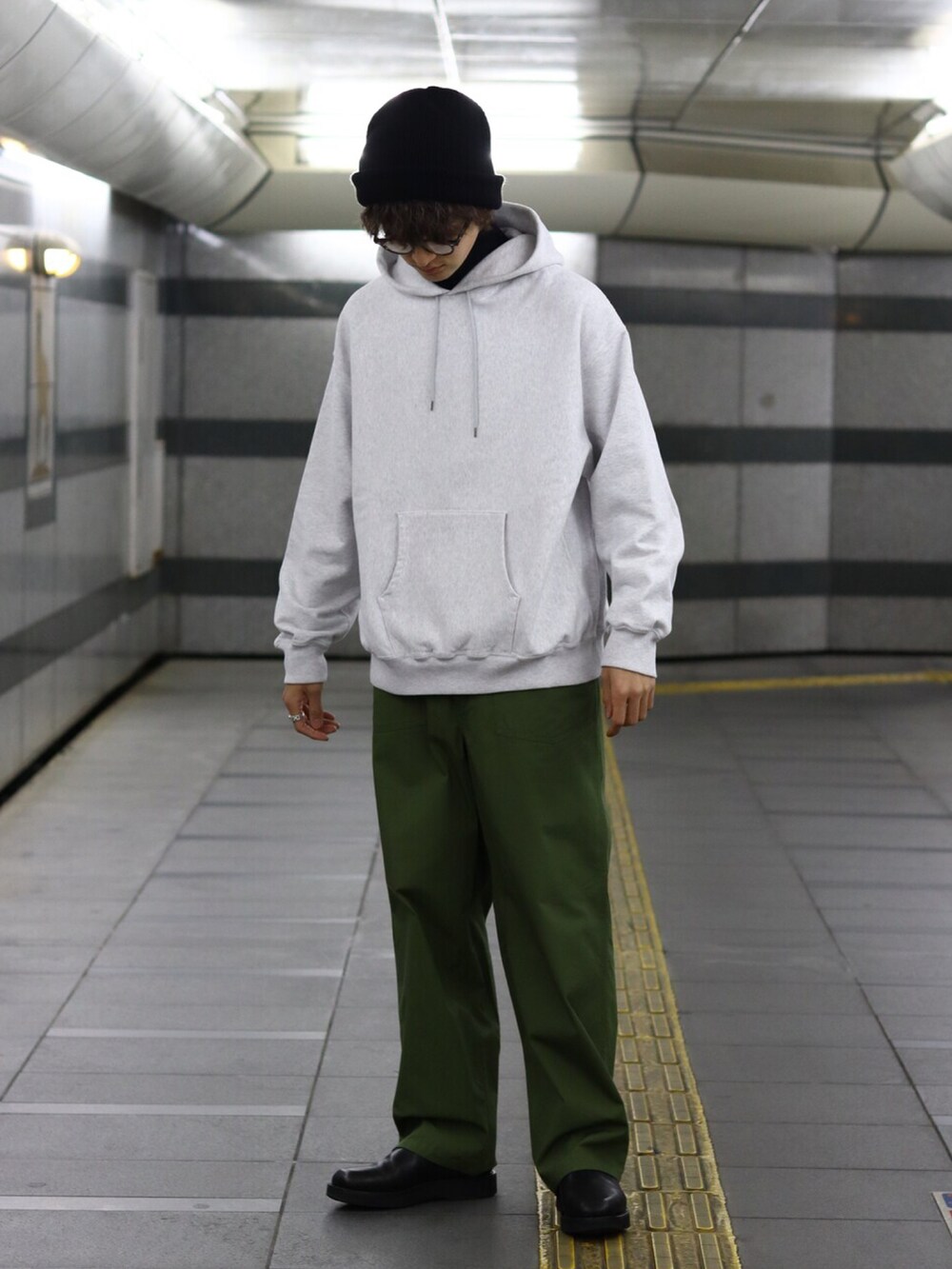 グレー系のパーカー、ベージュ系のトレンチコート、グリーン系のカーゴパンツを着用したメンズの冬コーディネートの2枚目の写真