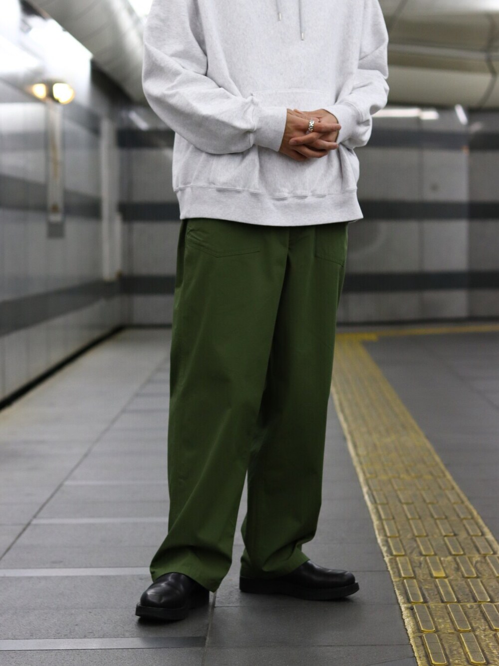 グレー系のパーカー、ベージュ系のトレンチコート、グリーン系のカーゴパンツを着用したメンズの冬コーディネートの3枚目の写真