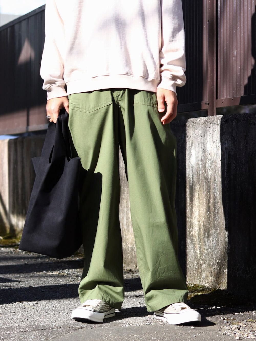 ベージュ系のブルゾン、グリーン系のカーゴパンツ、ブラック系のトートバッグを着用したメンズの冬コーディネートの2枚目の写真