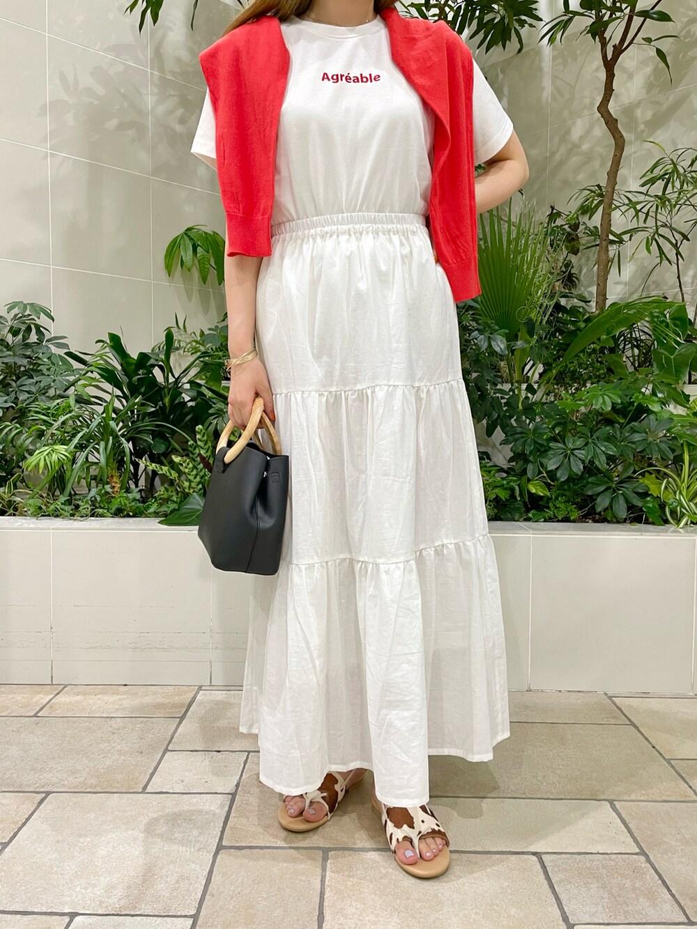 ブラック系のバッグ、ホワイト系のスカート、ホワイト系のTシャツ/カットソーを着用したレディースの春コーディネートの2枚目の写真