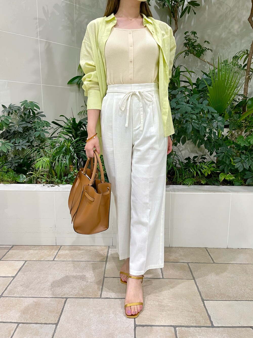 ブラウン系のバッグ、イエロー系のサンダル、ホワイト系のその他パンツを着用したレディースの夏コーディネートの3枚目の写真