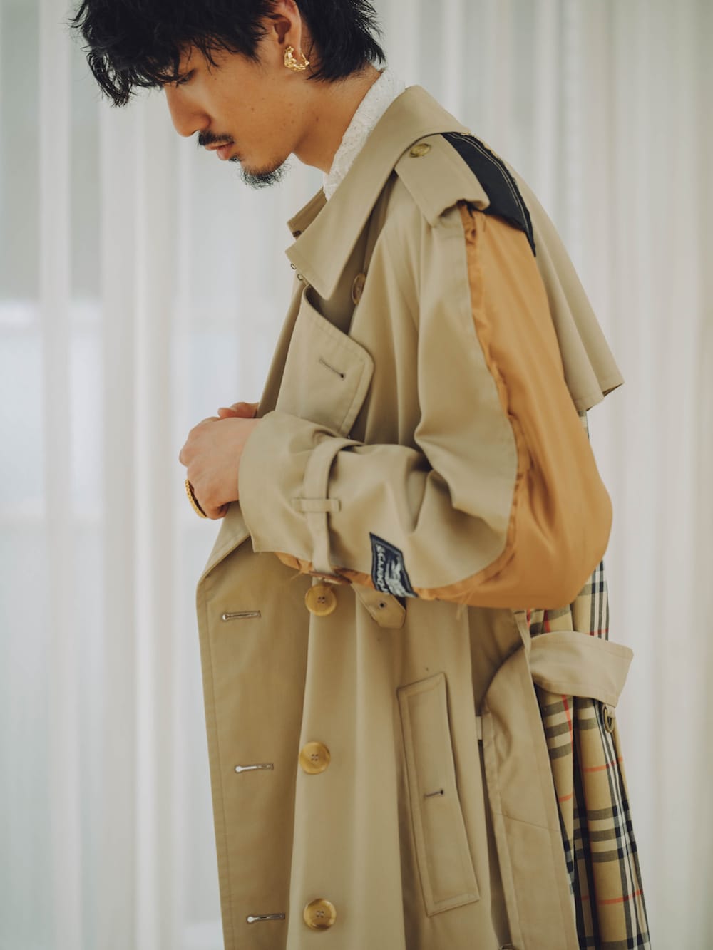 ベージュ系のトレンチコート、ブルー系のデニムパンツ、ブラウン系のローファーを着用したメンズの秋コーディネートの2枚目の写真