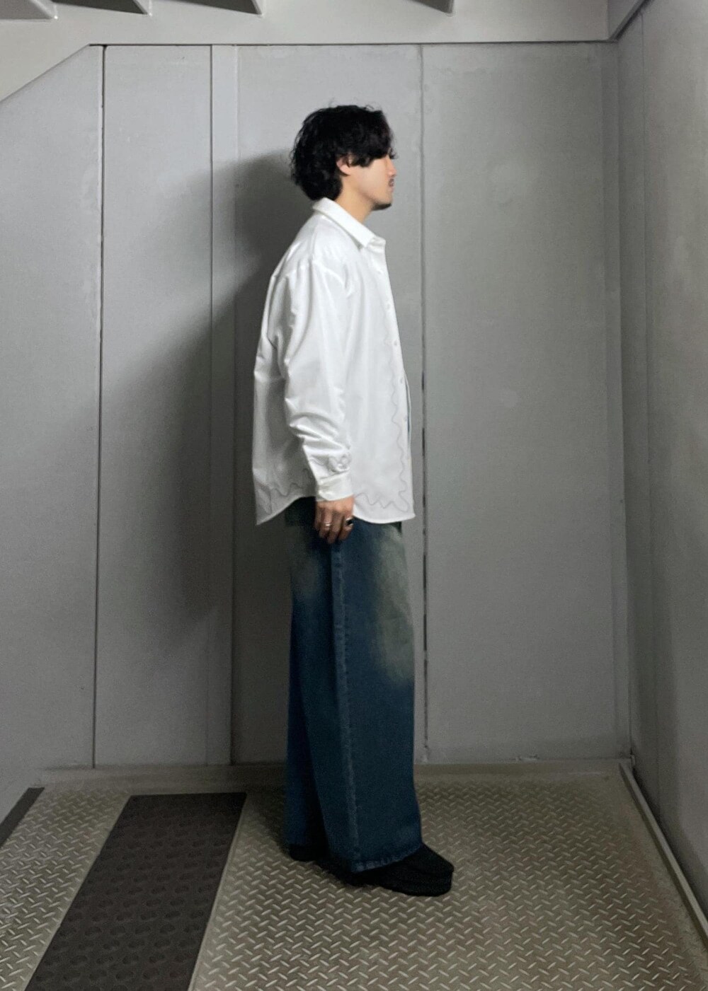 ブルー系のデニムパンツ、グレー系のニット/セーター、ホワイト系のシャツ/ブラウスを着用したメンズの冬コーディネートの2枚目の写真