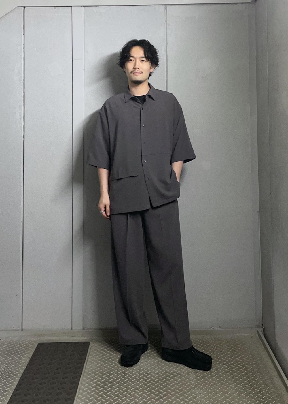 ブラック系のTシャツ/カットソー、グレー系のシャツ/ブラウス、グレー系のスラックスを着用したメンズの夏コーディネートの3枚目の写真