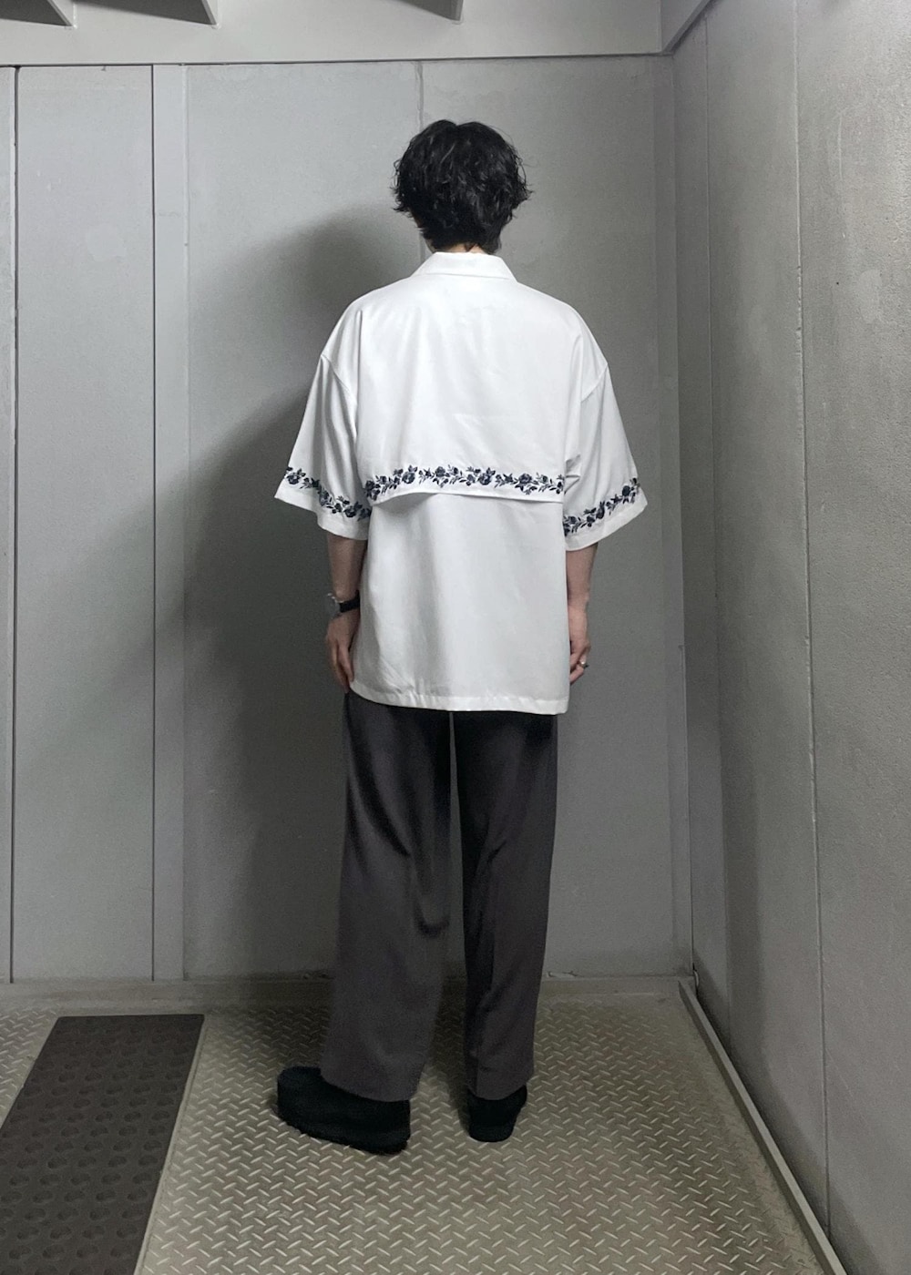 ブラック系のTシャツ/カットソー、ホワイト系のシャツ/ブラウス、グレー系のスラックスを着用したメンズの夏コーディネートの4枚目の写真