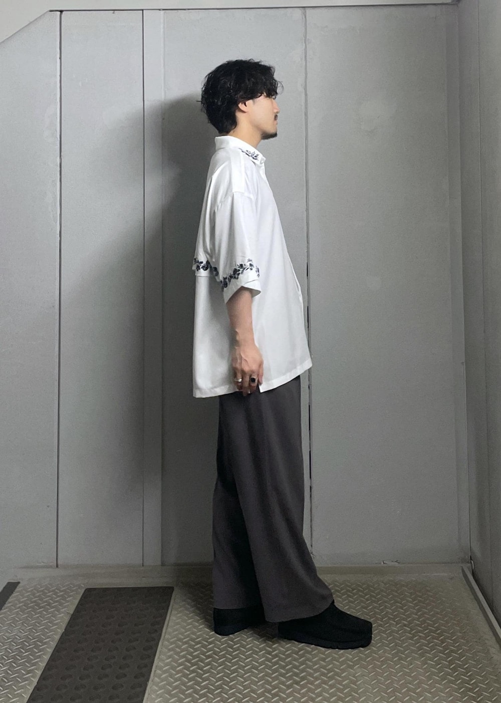 ブラック系のTシャツ/カットソー、ホワイト系のシャツ/ブラウス、グレー系のスラックスを着用したメンズの夏コーディネートの3枚目の写真