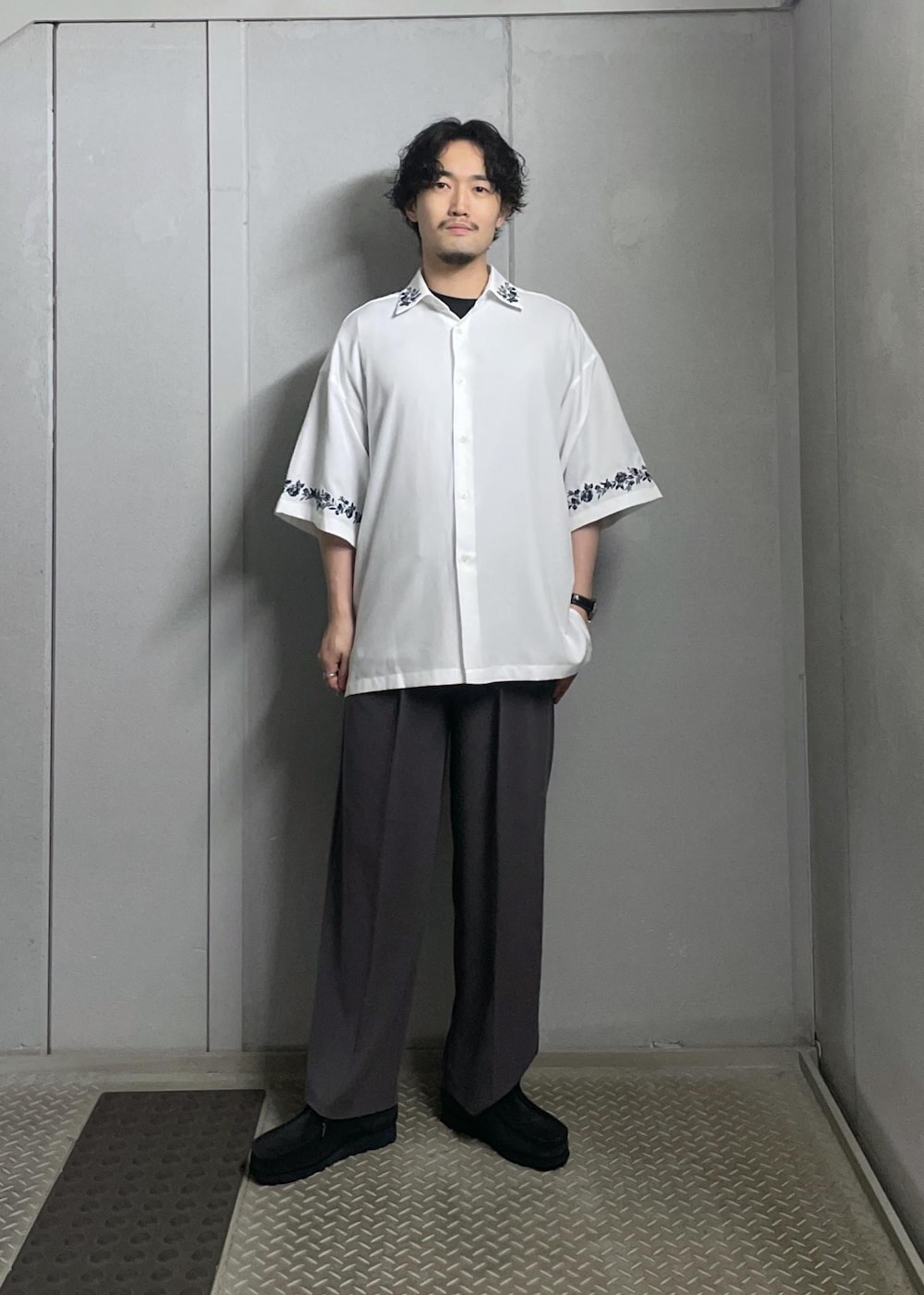 ブラック系のTシャツ/カットソー、ホワイト系のシャツ/ブラウス、グレー系のスラックスを着用したメンズの夏コーディネートの2枚目の写真