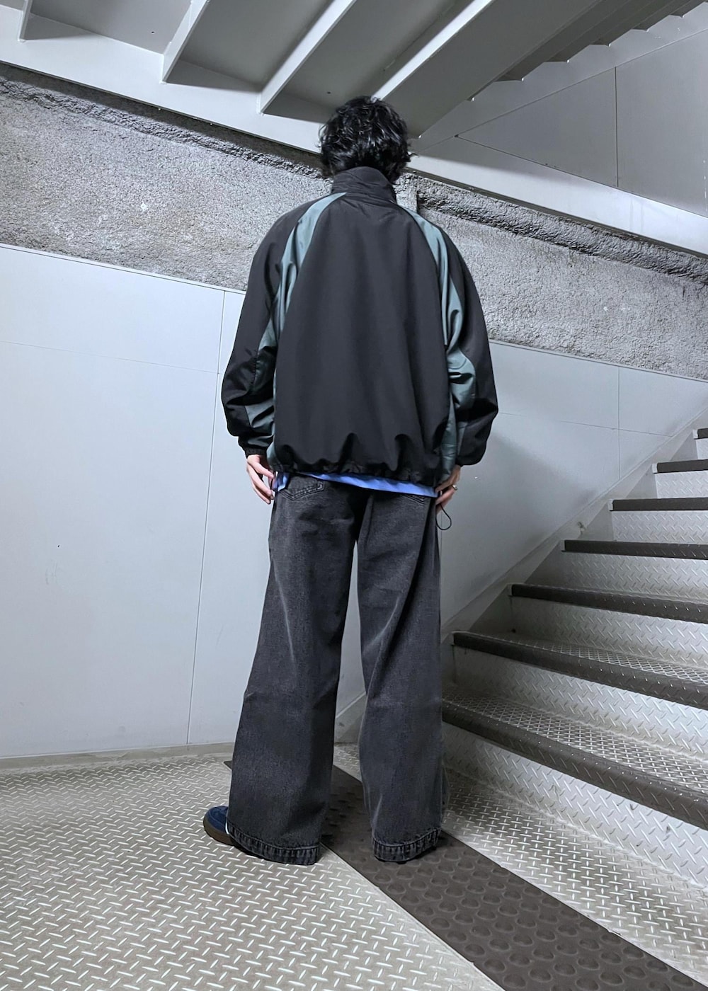 ブラック系のナイロンジャケット、ブラック系のデニムパンツ、ブルー系のシャツ/ブラウスを着用したメンズの冬コーディネートの3枚目の写真