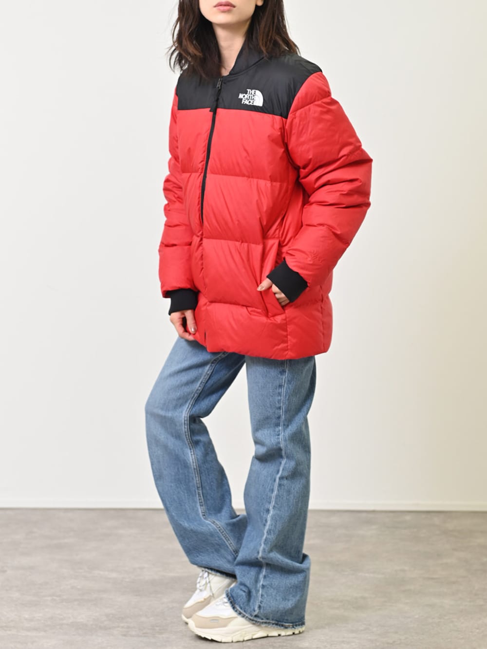 レッド系のダウンジャケット/コート、ブルー系のデニムパンツ、ホワイト系のスニーカーを着用したレディースの冬コーディネートの2枚目の写真
