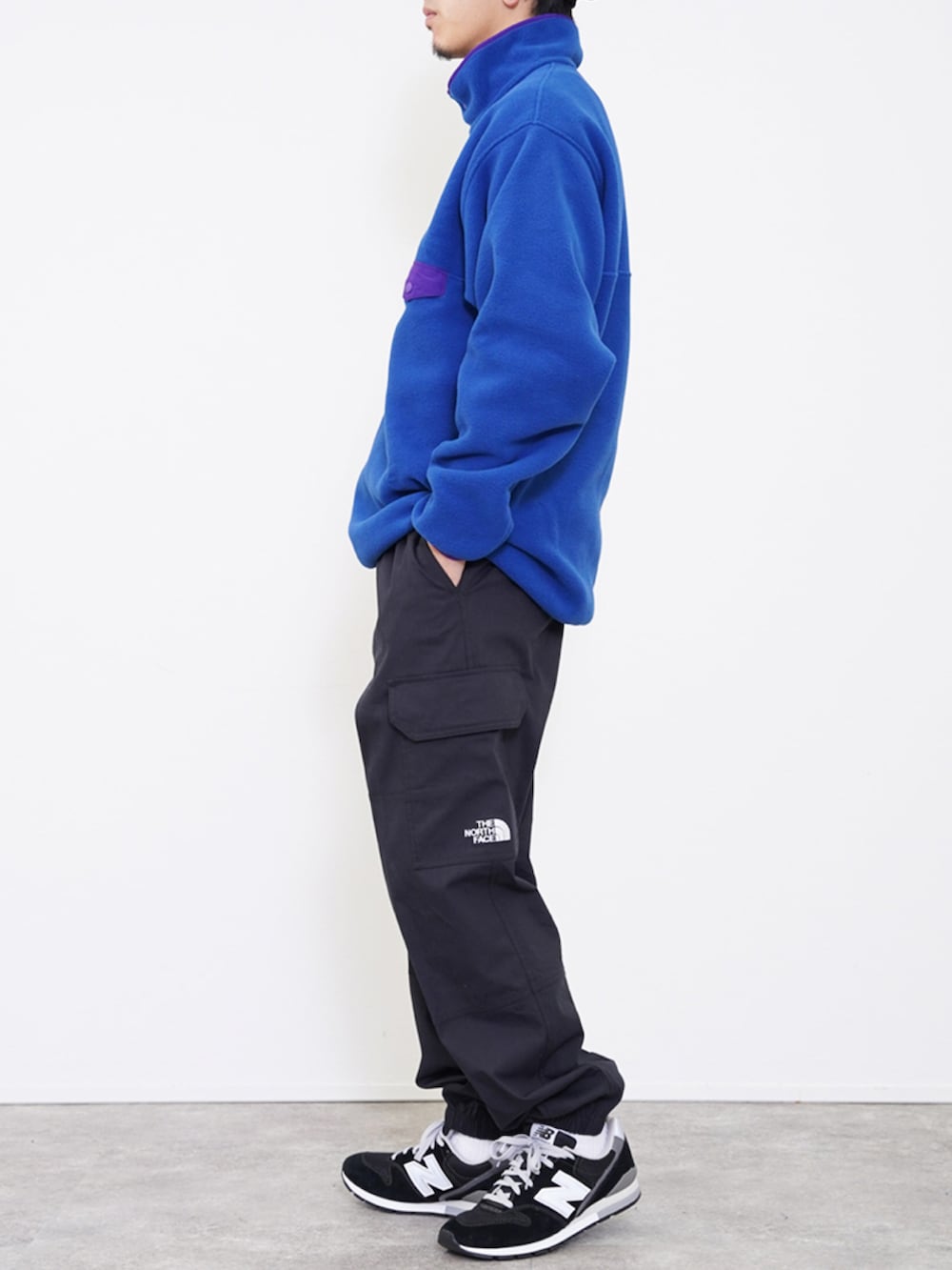 ブルー系のノーカラージャケット、ブラック系のカーゴパンツ、ブラック系のスニーカーを着用したメンズの冬コーディネートの2枚目の写真