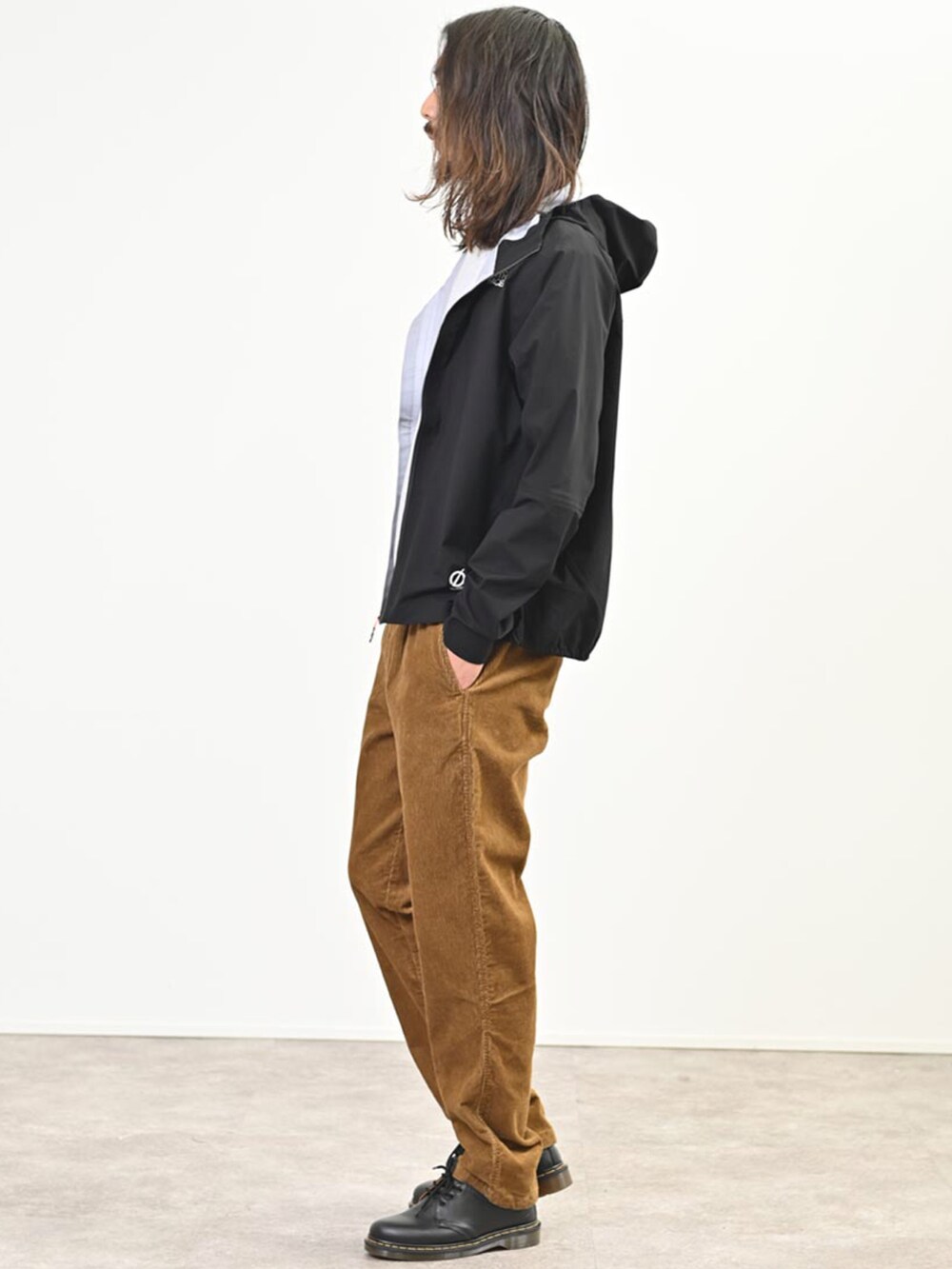 ブラック系のマウンテンパーカー、ブラウン系のその他パンツ、ブラック系のシューズを着用したメンズの春コーディネートの2枚目の写真