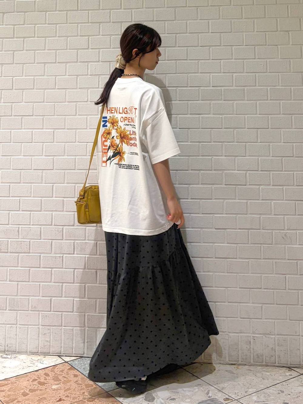 イエロー系のショルダーバッグ、ブラック系のサンダル、ホワイト系のTシャツ/カットソーを着用したレディースの夏コーディネートの3枚目の写真