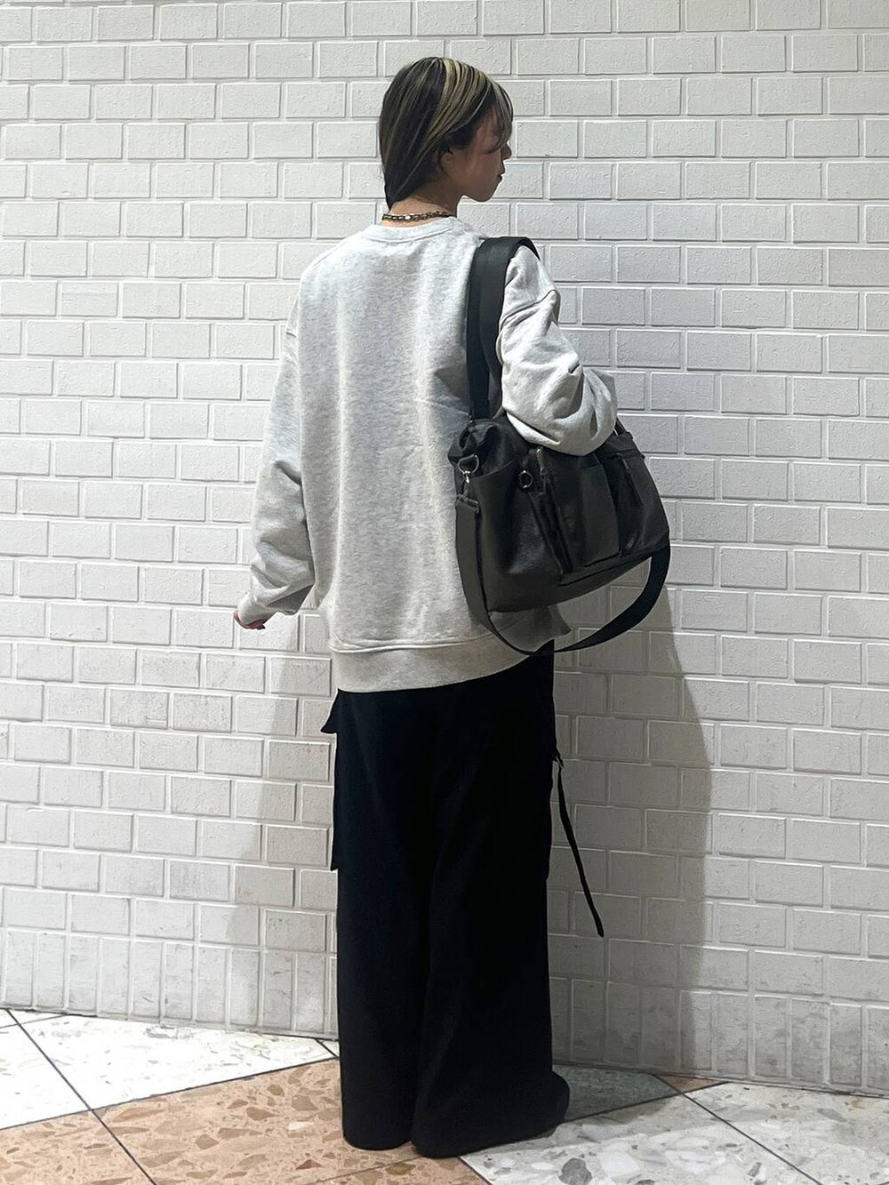 グリーン系のボストンバッグ、ブラック系のスラックス、グレー系のスウェットを着用したレディースの冬コーディネートの5枚目の写真
