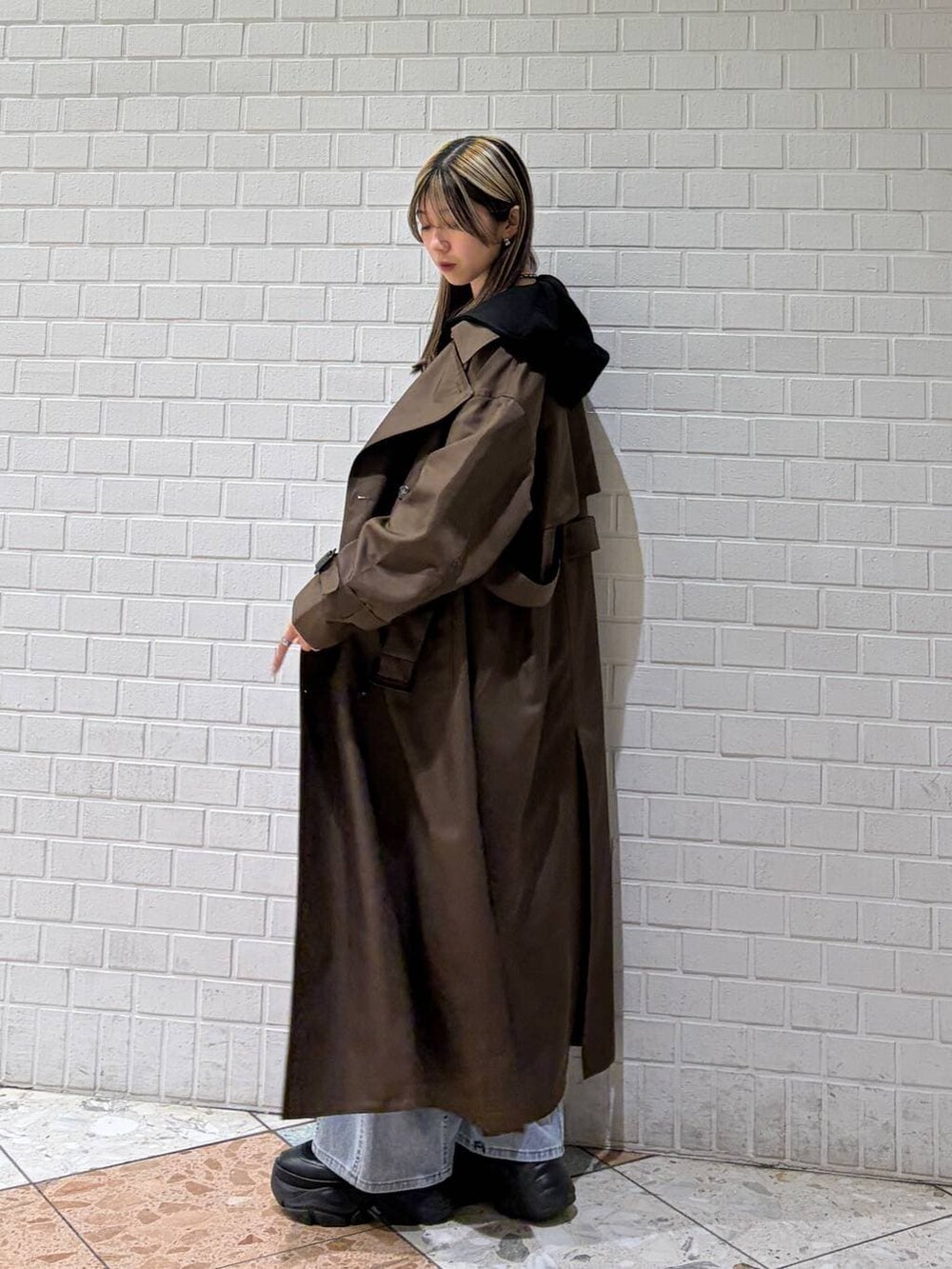 ブラック系のブーツ、ブラウン系のトレンチコート、ブルー系のデニムパンツを着用したレディースの春コーディネートの5枚目の写真