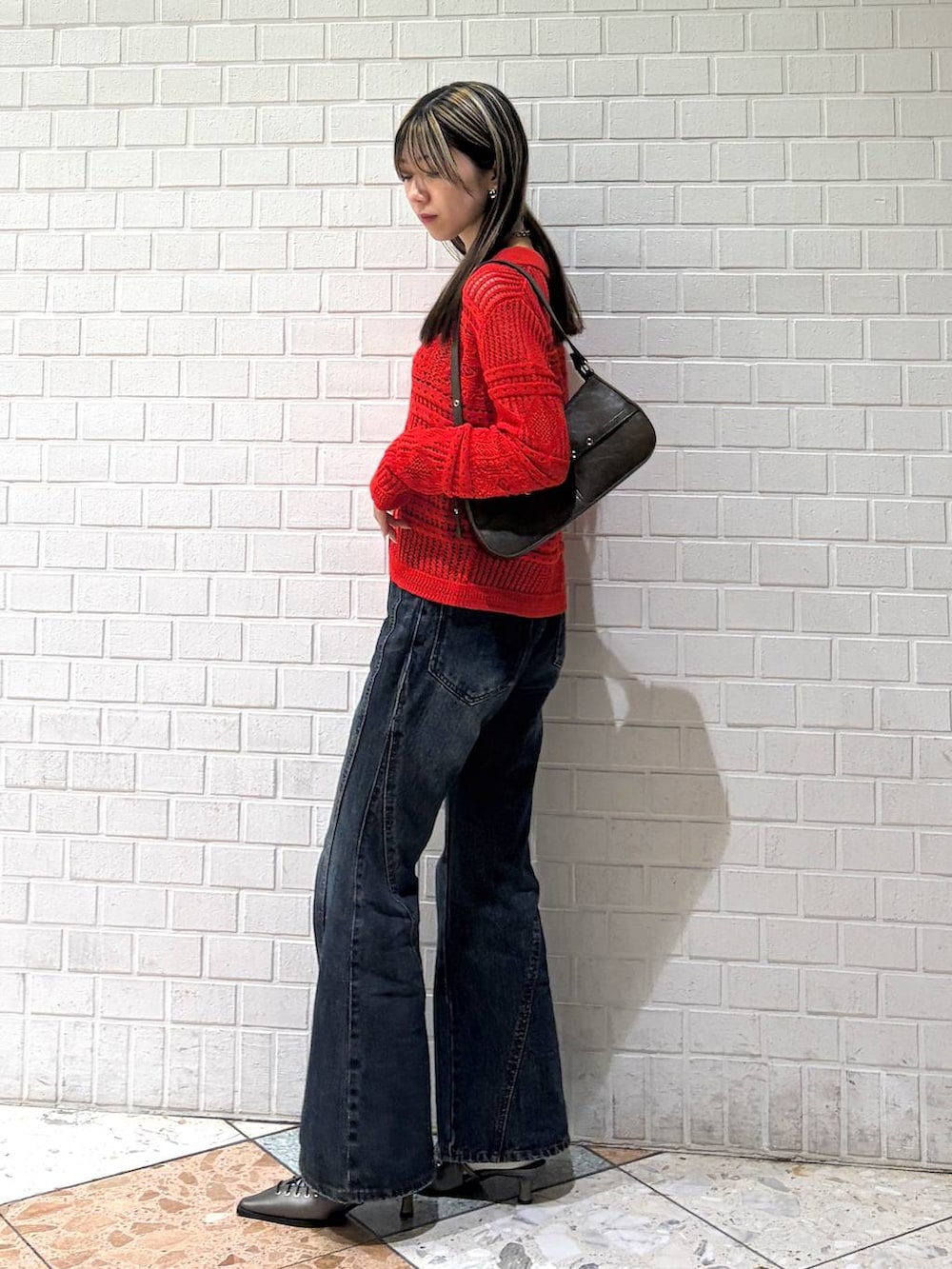 ブルー系のデニムパンツ、ブラウン系のハンドバッグ、ブラウン系のサンダルを着用したレディースの春コーディネートの2枚目の写真