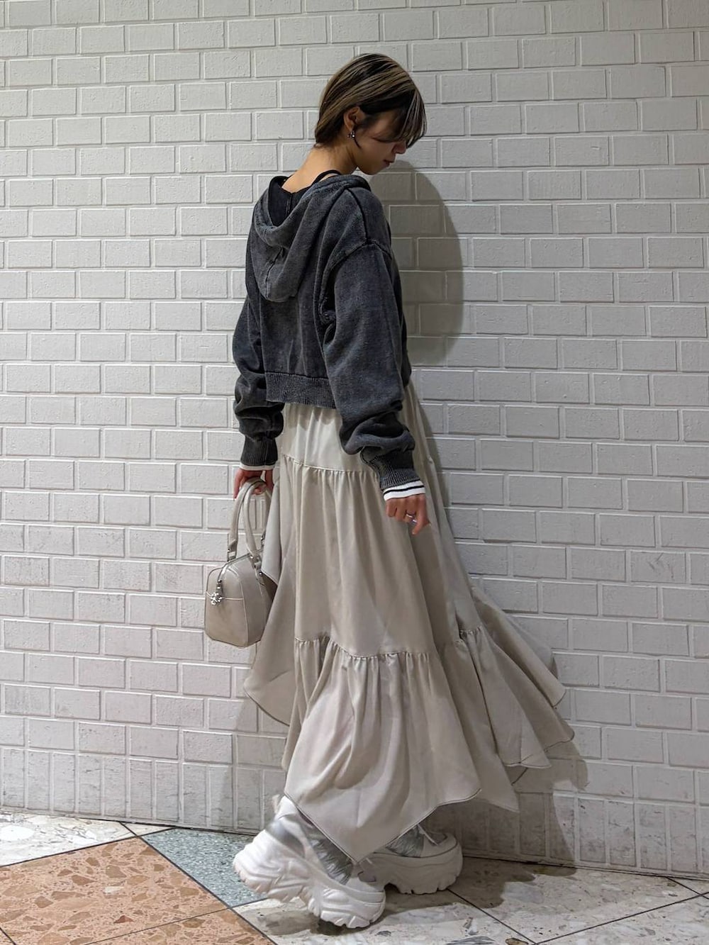 ホワイト系のスニーカー、ベージュ系のスカート、ホワイト系のボストンバッグを着用したレディースの冬コーディネートの6枚目の写真