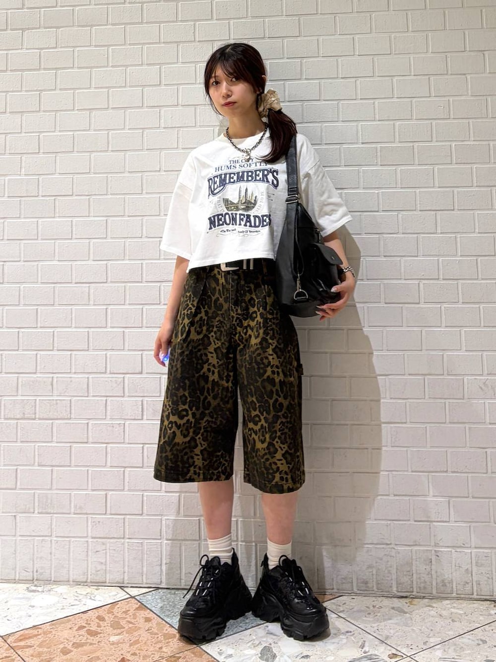 ブラック系のスニーカー、ブラック系のショルダーバッグ、ホワイト系のTシャツ/カットソーを着用したレディースの夏コーディネートの7枚目の写真