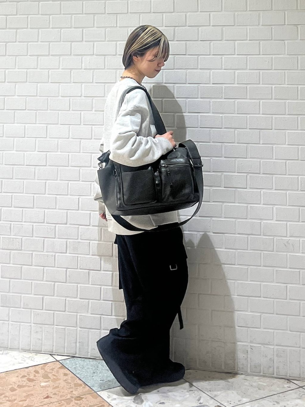 グリーン系のボストンバッグ、ブラック系のスラックス、グレー系のスウェットを着用したレディースの冬コーディネートの2枚目の写真
