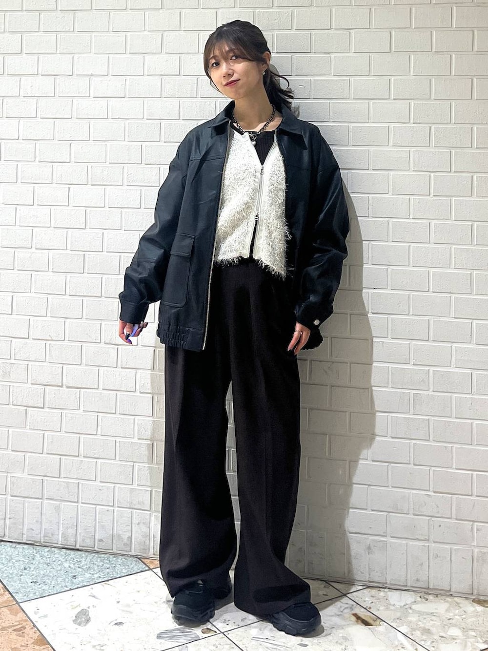 ブラック系のスニーカー、ブラック系のブルゾン、ホワイト系のカーディガン/ボレロを着用したレディースの秋コーディネートの6枚目の写真