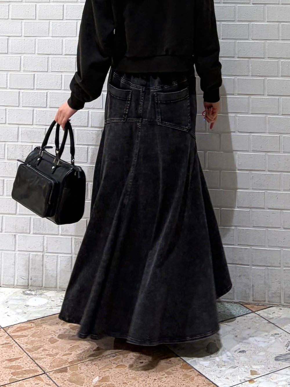 グレー系のスウェット、ブラック系のショルダーバッグ、ブラック系のデニムスカートを着用したレディースの春コーディネートの8枚目の写真