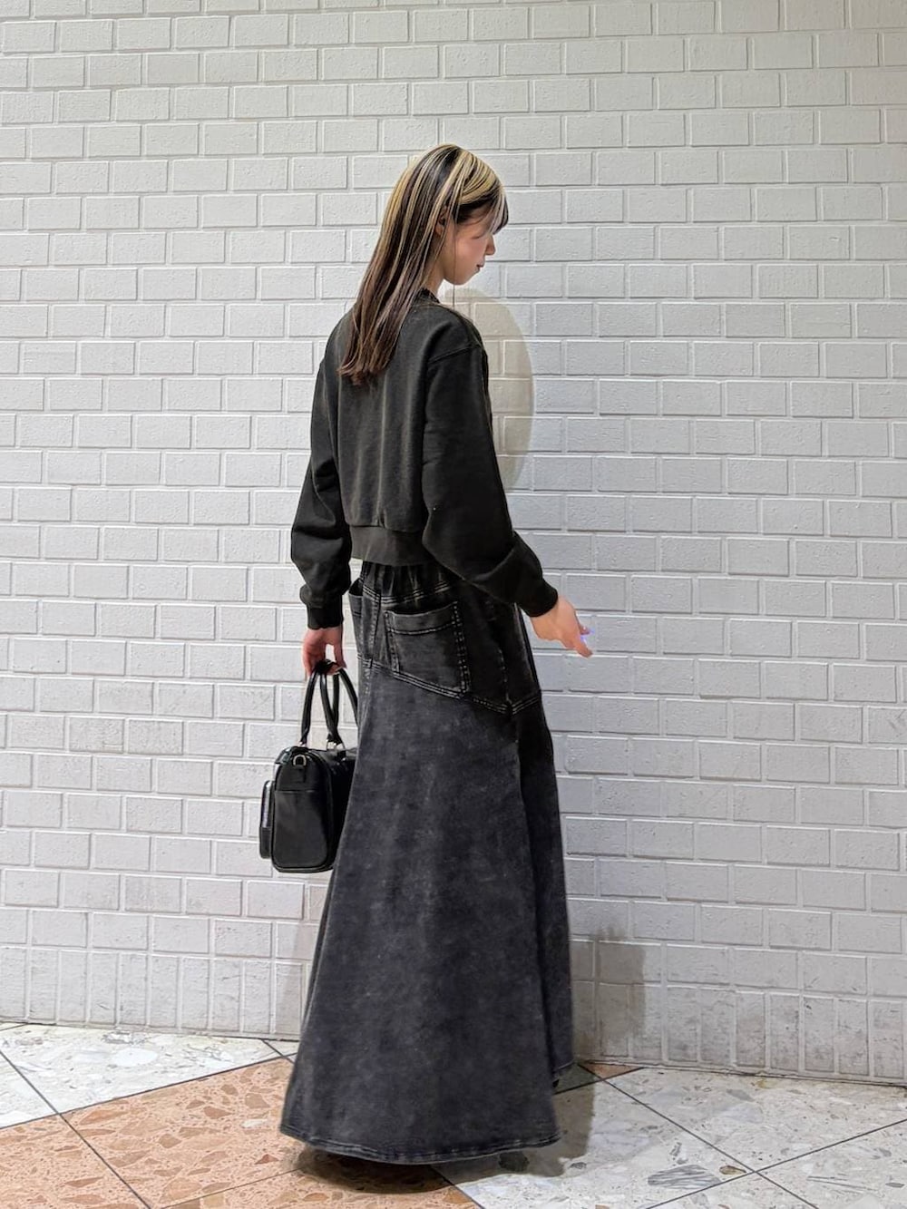 グレー系のスウェット、ブラック系のショルダーバッグ、ブラック系のデニムスカートを着用したレディースの春コーディネートの6枚目の写真