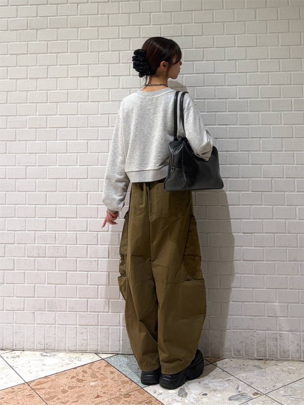 グレー系のスウェット、グリーン系のカーゴパンツ、ブラック系のブーツを着用したレディースの秋コーディネートの2枚目の写真
